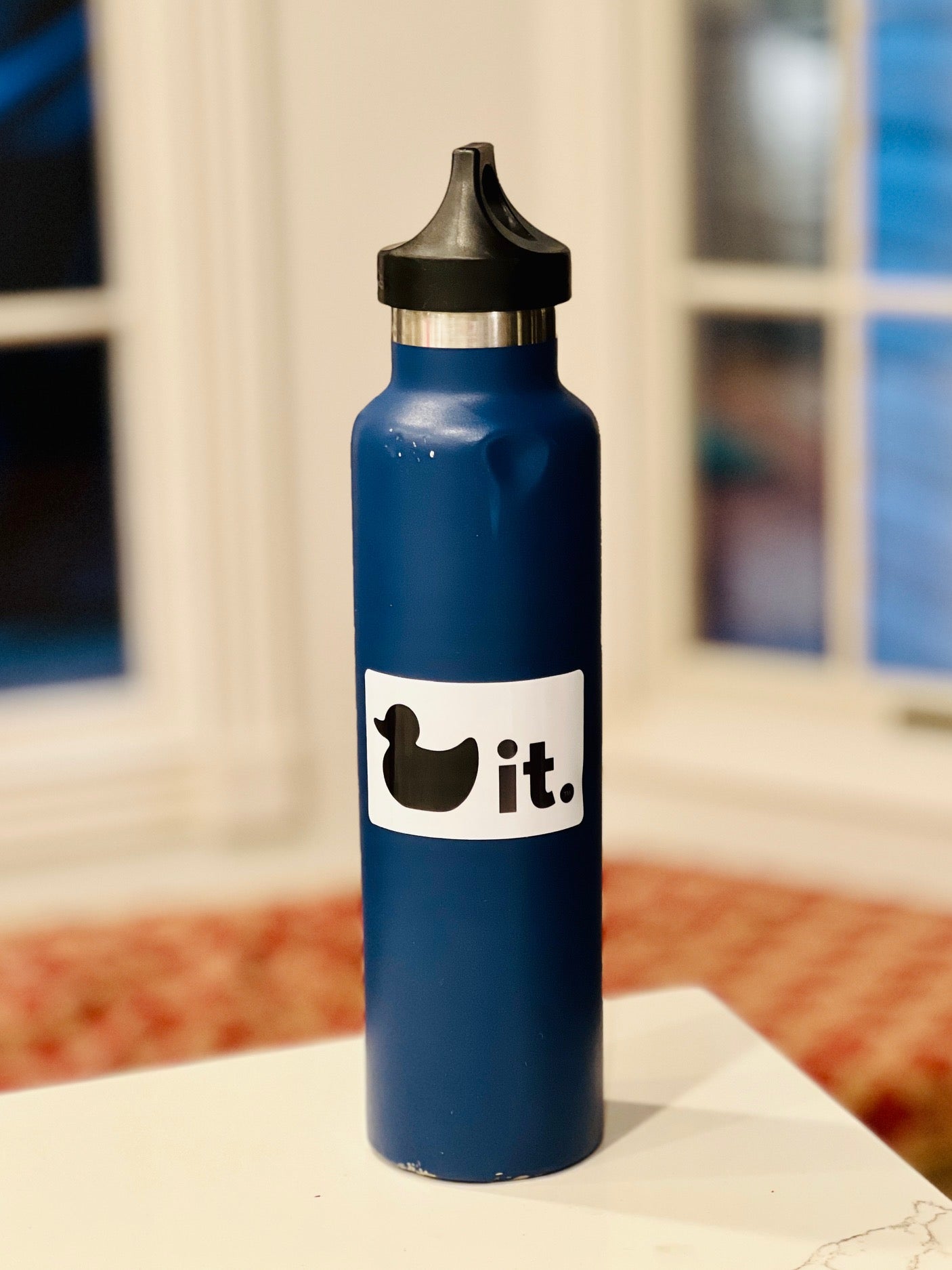 Duck it logo sticker 2 x 3 inches on blue water bottle